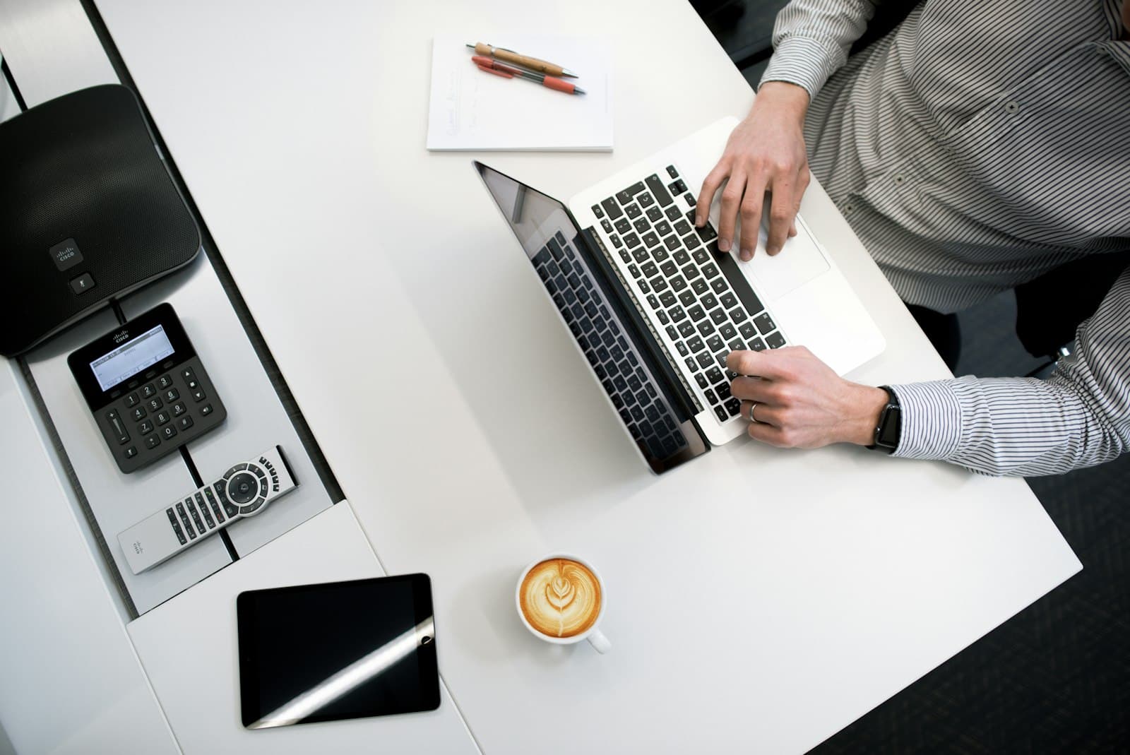 Overhead view of a desk with a laptop, phone and coffee
