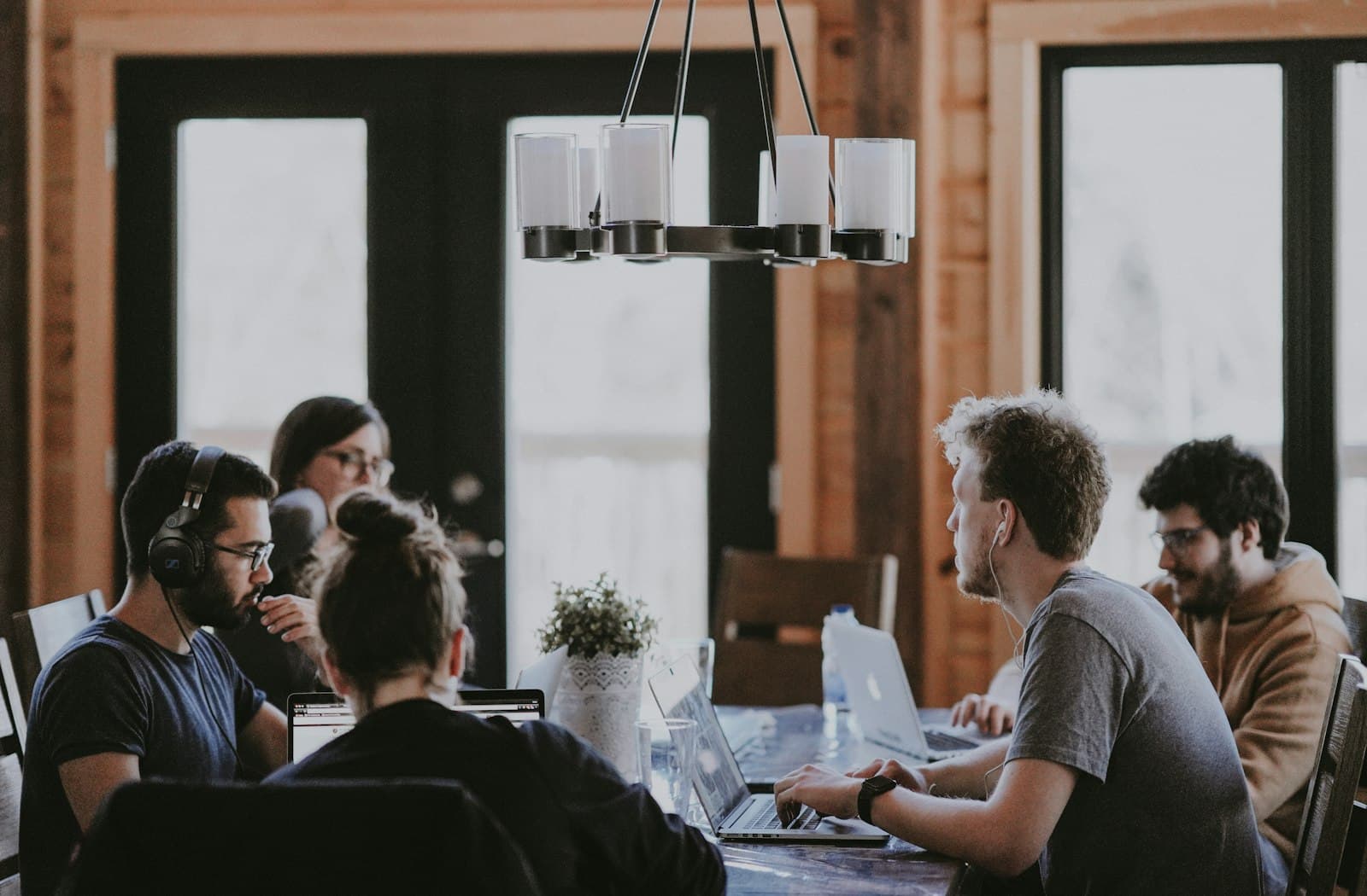 Photo: Annie Spratt, Unsplash Four people around a table in a bright meeting room, talking through notes and laptops