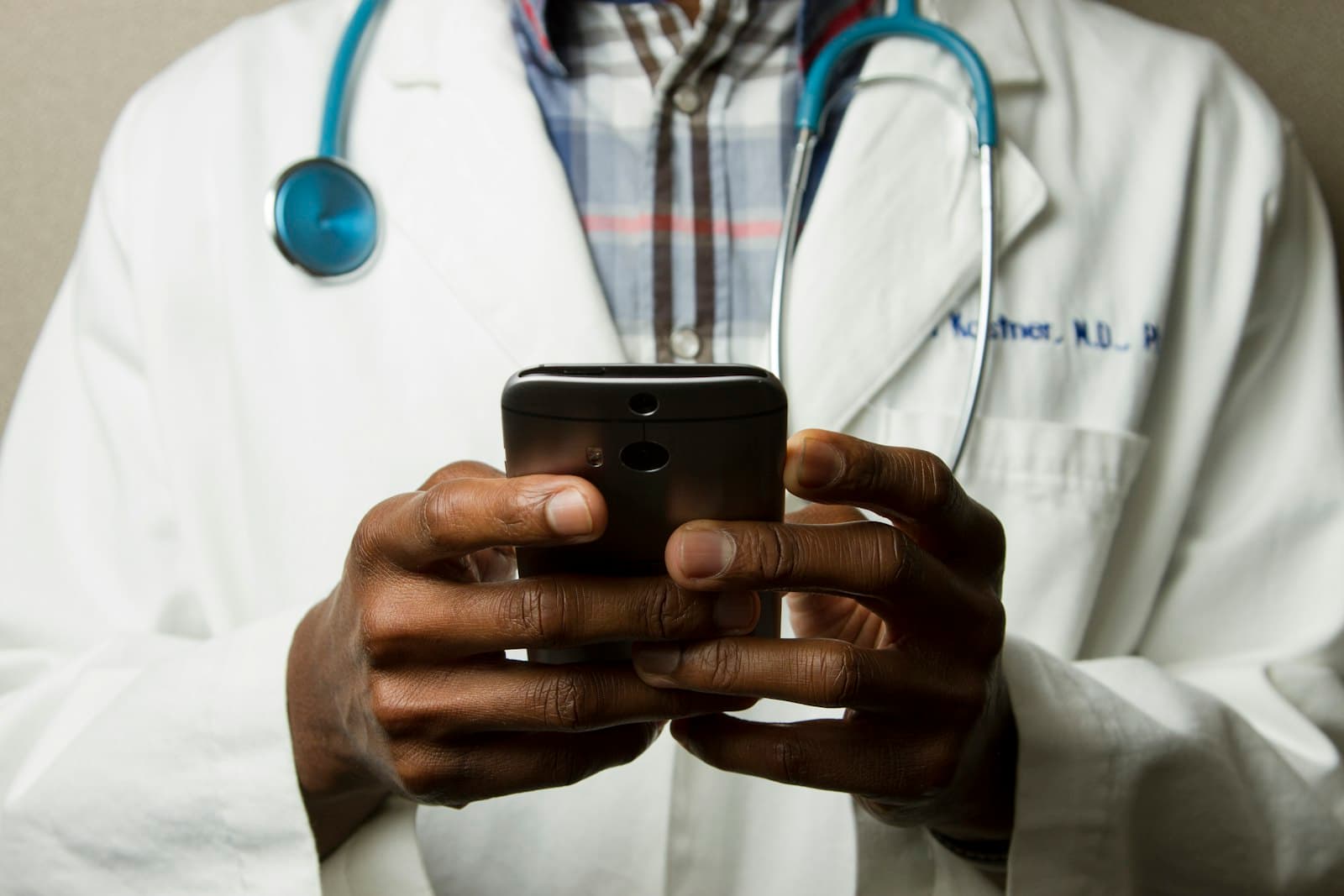 Photo: National Cancer Institute, Unsplash A clinician in a white coat using a smartphone