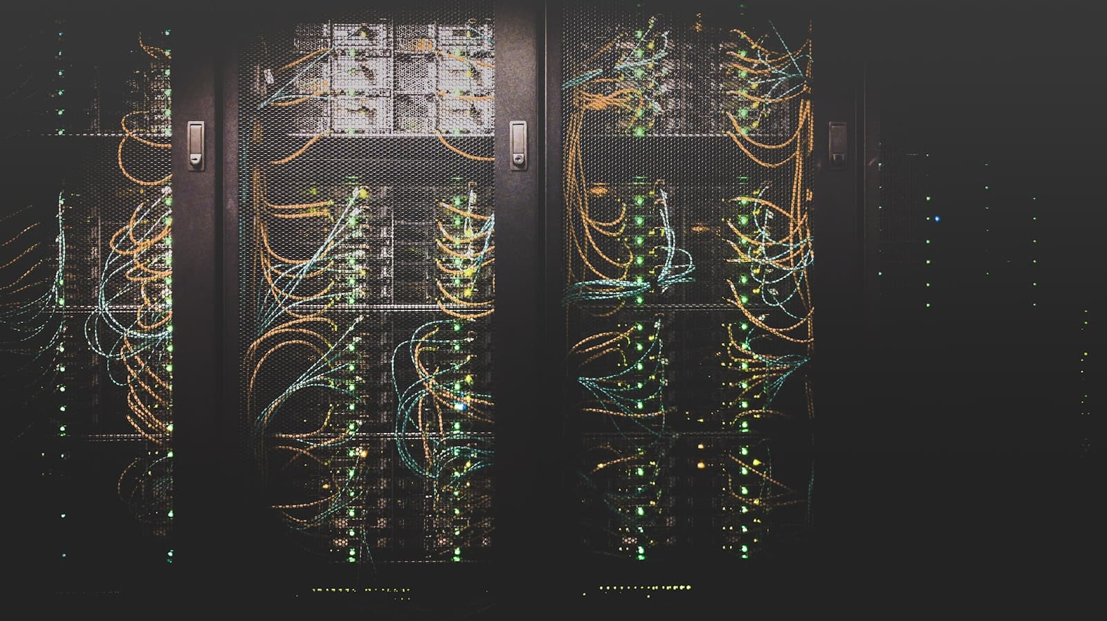 Photo: Taylor Vick, Unsplash Rows of servers in a data centre with cabling lit by status lights