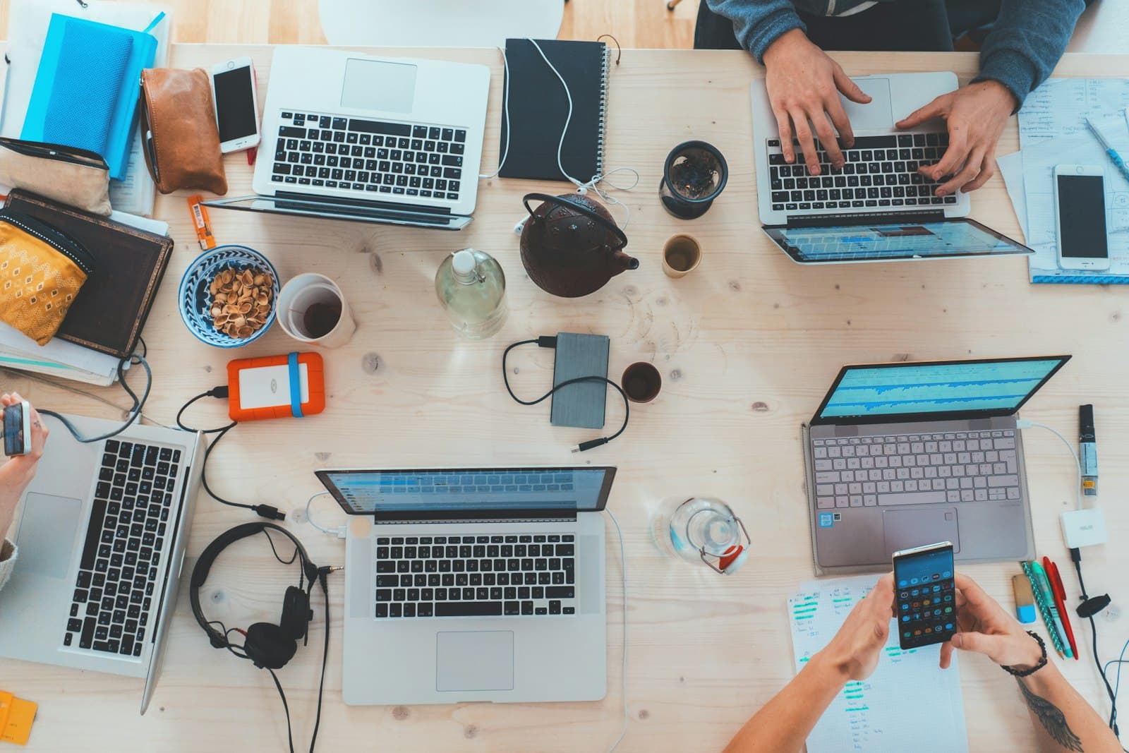 Photo: Marvin Meyer, Unsplash Overhead view of a shared desk with several laptops and notebooks in use